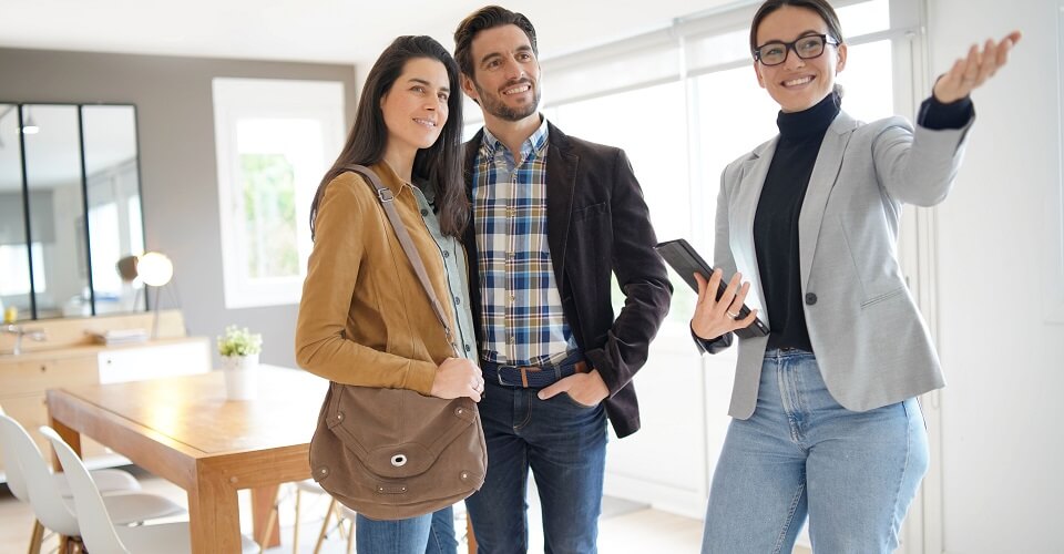 A couple and a woman are talking inside a house